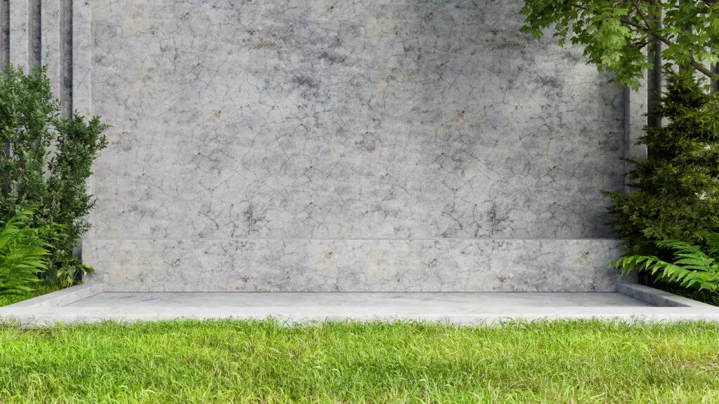 Textured concrete wall and patio bench set in a green lawn outdoor space.